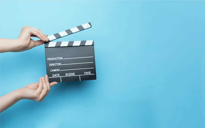 Videodreh: Eine Person hält eine Filmklappe in der Hand.